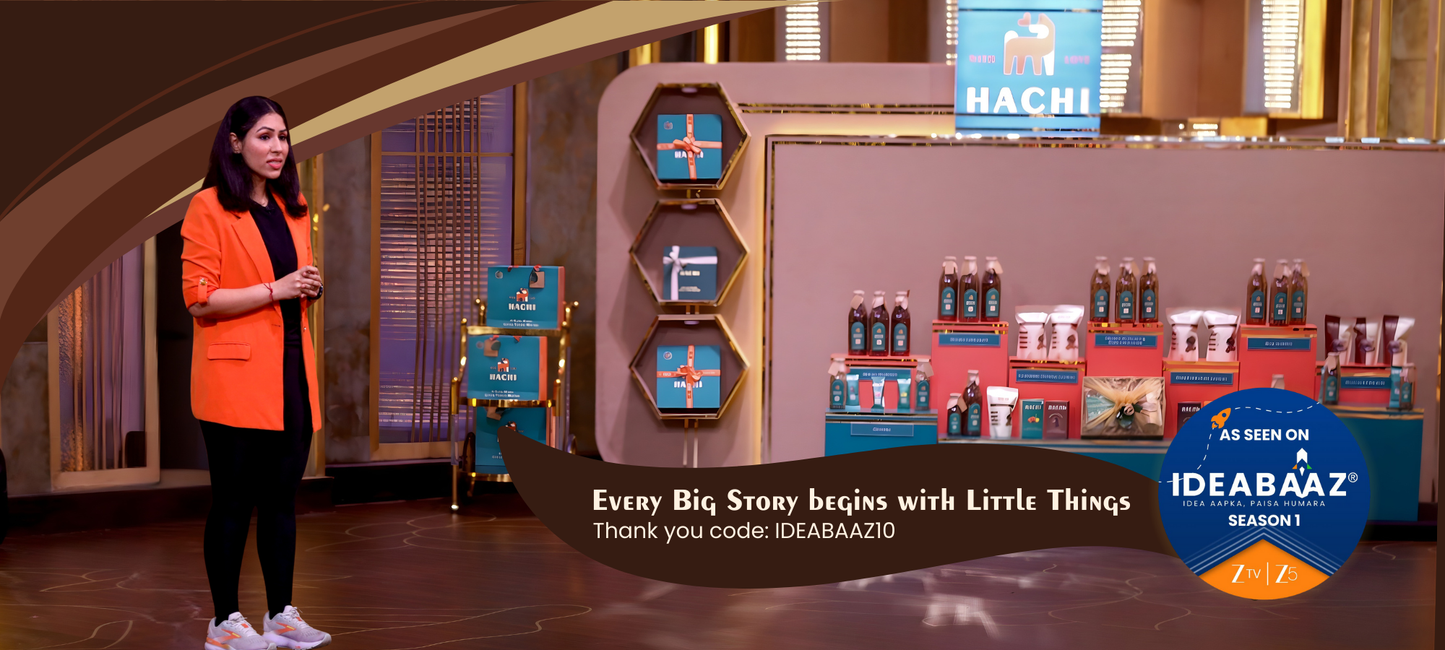 Founder of Hachi in orange blazer standing in front of a display with HACHI products on zee TV Ideabaaz stage.
